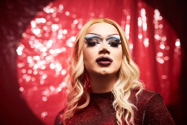 Drag queen in front of red backdrop